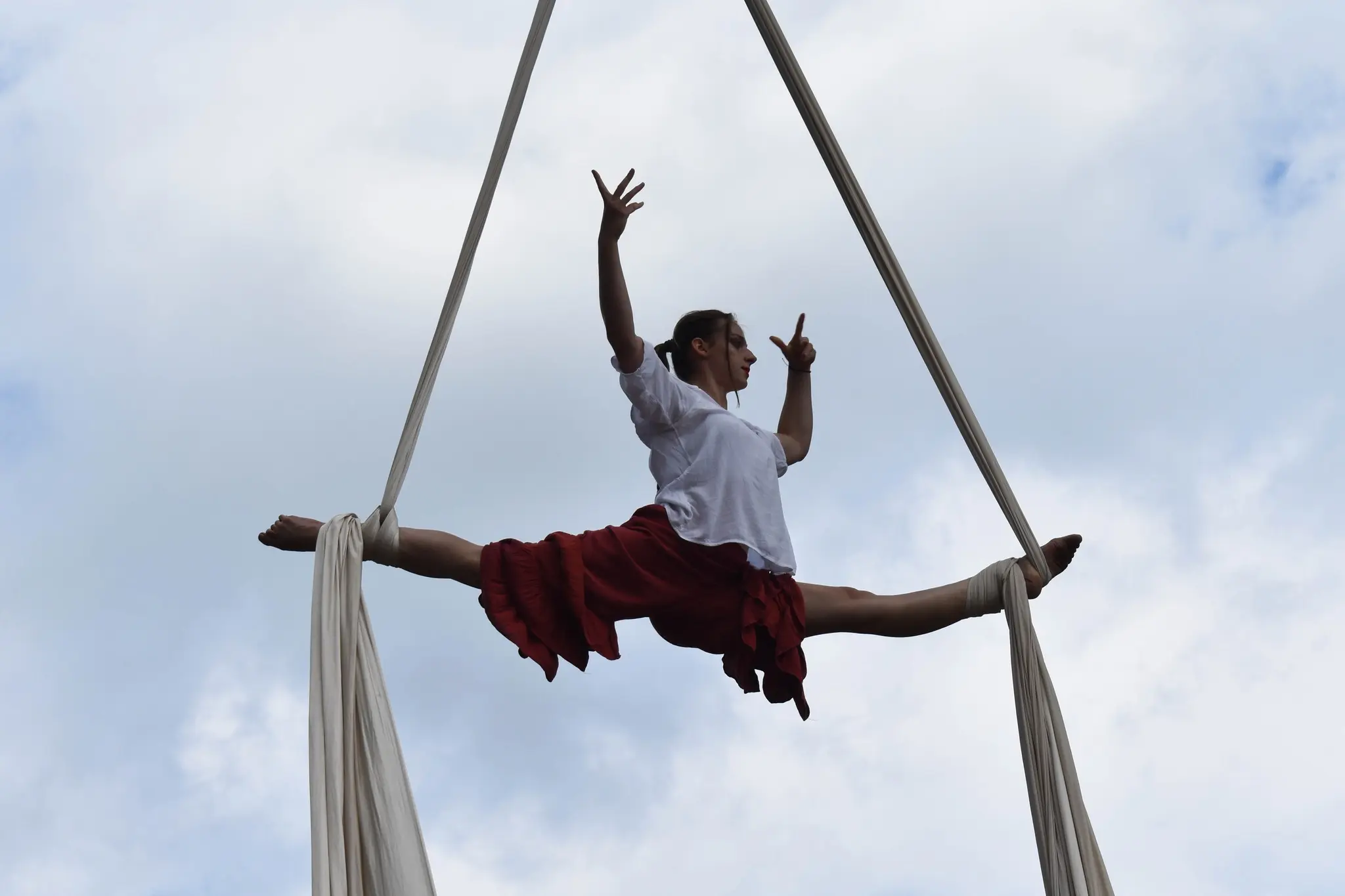 Akrobatka powietrzna wykonująca szpagat na szarfach w górach na tle panoramy Tatr.